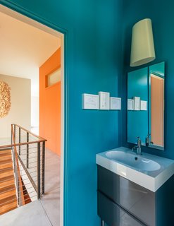 A Fun, Cost-Conscious Home With Bright Interiors and a Climbing Wall - Photo 7 of 9 - A Kite wall sconce by Foscarini and mirrors from Gedy by Nameeks are installed above a polished chrome faucet from Kohler’s Purist collection.