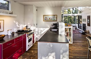Bright Renovation of a 1970s Big Sur Home - Photo 7 of 10 - This house in Carmel by the Sea is enlivened by its very red kitchen cabinetry. By knocking down a dividing wall, the architects opened the kitchen up to the rest of the living space. Ikea red lacquer cabinetry and Caesarstone countertops replace dingy cupboards and old-fashioned finishes. Stainless steel appliances help ground the airy, open space.
