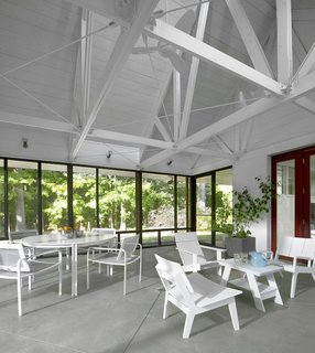 The 400-square-foot porch, a central focus of the home, was wrapped in a Kawneer window framing and screen—probably the biggest material indulgence. A south-facing skylight above the porch draws in air and ventilates the entire cottage, dropping temperatures about 10 degrees. The table-and-chair set on the left is by Brown Jordan, while the coffee table and chairs are from Sojourn in Sawyer, Michigan.