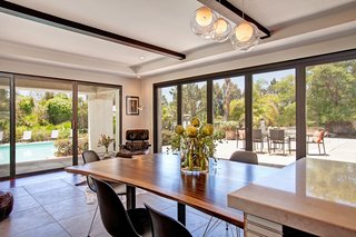 The designers handmade the custom table with meticulous attention to detail. After intentionally matching wood grains to ensure a smooth transition between pieces, the table was fitted into the kitchen island to transition the kitchen into the living area. The dining chairs and lounger are Eames for Herman Miller.
