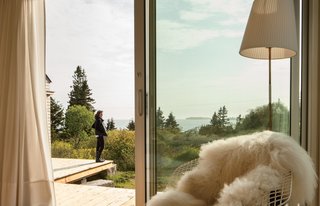 A Cluster of Cabins in a Former Quarry Makes a Simple Vacation Escape - Photo 5 of 13 - Resident Nadja van Praag enjoys the view from the deck that connects the trio of structures. The idea for the deconstructed plan was inspired in part by Alvar Aalto sketches of a "peeled apart" summer cabin, says architectural designer Riley Pratt, in which interconnected volumes surround a central courtyard.