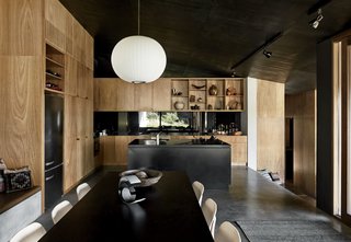 The kitchen island is made from oxidized steel with a honed black marble benchtop. Cabinetry in blackbutt, an Australian hardwood known for its fire resistance, contrasts with the dark interiors.