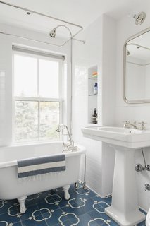 A salvaged antique tub stands beside a sink by Waterworks. Town and Country Surfaces supplied the Malaga cement tiles that color the floor.