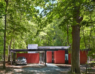 Topped with translucent polycarbonate roof panels, the carport and storage shed helps buffer the home from the road. "It’s part of easing into the site with increasing enclosure along the entry axis," Hart says. "We created a purposefully drawn-out experience that’s intended to heighten awareness of the site and gradually transition from the forest to the home."