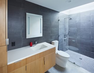 Made of stained beech wood with pulls by Mockett, the bathroom vanity was custom-designed by the architects. A Caesarstone counter, Toto sink fixture, Tech Lighting mirror, and Kohler toilet and sink are surrounded by Mosa tiles.