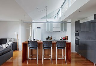 Inside, bar stools by Anibou, appliances by Miele, and gray cabinets from IKEA furnish a simple kitchen.
