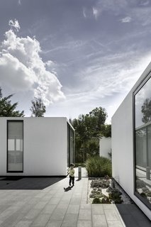 The project title "Casa 4.1.4" refers to the four main volumes, one central plaza, and four patios. This simple configuration creates distinct, private spaces tied together with open-air common areas.