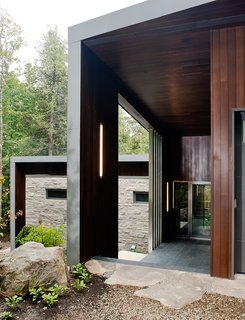 A Tranquil Lakeside Abode in Quebec Unfolds Over Six Levels - Photo 3 of 9 - Tremblay chose materials that would reflect the natural setting, like the Polylam-C cedar siding from Prorez, used at the home’s entrance. The exterior floor finish is Montauk grey slate.