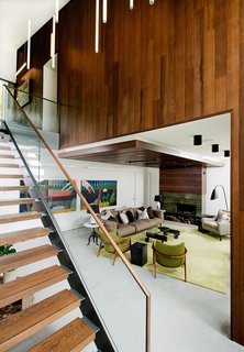 A Tranquil Lakeside Abode in Quebec Unfolds Over Six Levels - Photo 5 of 9 - Continuity of exterior and interior materials can be seen in the living room, which is framed by the same Prorez cedar siding as outside. It complements a wood fireplace by Stûv, which is finished with bamboo verde stone and Montauk grey slate.