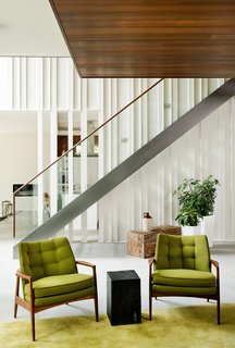 A Tranquil Lakeside Abode in Quebec Unfolds Over Six Levels - Photo 6 of 9 - Raw wood planks were painted white and fitted next to a staircase and banister by Bättig Design. Matching chairs by Thayer Coggin sit atop a Crate and Barrel rug.