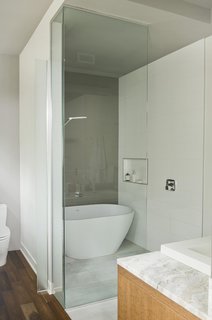 A Tranquil Lakeside Abode in Quebec Unfolds Over Six Levels - Photo 8 of 9 - An Emily quartz bathtub by Caml-Tomlin is surrounded by Ceragres’ fade and frammenti tile.