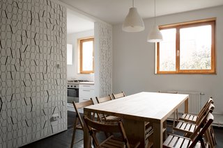 Chairs and lights from IKEA accompany a custom dining table, which incorporates shelving and storage space underneath.