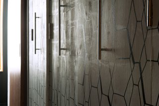 Like the nearby dining room wall, this custom-made wood storage space was painted white then enhanced with a geometric pattern, drawn on with black felt-tip pens. Cabinet handles from Leroy Merlin complement the graphic design.