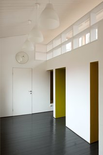 Inspired by "polati," a sleeping loft that featured prominently in traditional Russian homes, Le Atelier created a series of tiny bedrooms that connect to a playroom with a study upstairs. A clock and lights from IKEA blend into the room’s simple color palette.