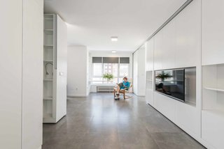 Transforming a choppy and dated flat in Salinas, Spain, Madrid-based PKMN Architectures designed a space with internal walls and partitions that rotate effortlessly to meet different needs. Depending on the configuration, the home can be used as a two-bedroom, one-bedroom, or open studio space for parties or gatherings. Dated parquet floors were replaced with modern ceramic tile. All walls and ceilings were re-plastered, and old windows were upgraded with energy-efficient, double-glazed glass.