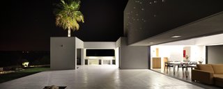 A Home That Dramatically Replicates a Starry Sky in Its Living Room - Photo 5 of 9 - One of the homeowners’ priorities was removing the barrier between interior and exterior in an effortless and low-maintenance way. The enormous gray resin-finished patio offers both durability and the opportunity for gorgeous al fresco dining.