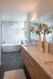 Edgewood cabinets adjoin countertops made from Carrara marble in the master bathroom. A Wyndham Collection bathtub sits under a chrome showerhead by Moen.