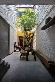 15 Brilliant Designs That Work Around Nature - Photo 13 of 15 - The family enjoys a shared meal in the ground floor alleyway, which serves as a gathering place, dining area, and playground. Native trees are planted on the ground floor as well as on balconies and in the steel frames, covering the home with plants and shifting the natural world inside.