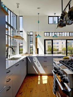 20 Best Modern Kitchen Counters - Photo 19 of 20 - The kitchen of this Bay Area houseboat is marked by its Wolf gas range, white Carrara marble countertop bar, and Cobb Rise & Fall pendants by Original BTC. The architect designed a custom wine glass holder, which hangs nearby.