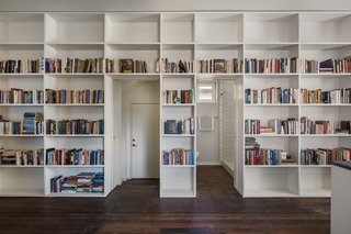 10 Ways to Solve Storage Problems in Small Spaces - Photo 7 of 10 - If you're a collector, find a way to highlight your passion without impeding on space. In this example, the residents' book collection resides in a wall of built-in shelving running the length of the room. The additional thickness of the bookshelves and the books provide acoustic separation between the hustle and bustle of the kitchen and the bedrooms. 