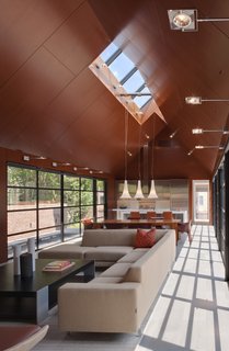 Pietra Serena tiles unite the living room, dining room, and kitchen under a mahogany ceiling. San Siro Wall Lamps by De Majo surround a Monti sectional sofa by Dellarobbia.