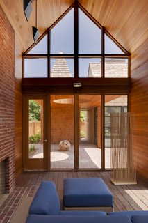 A Douglas fir ceiling in the screened porch and red bricks are accented by blue Arizona modular outdoor seating by Barlow Tyrie.