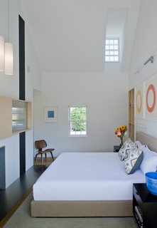 "In this project, the interior walls and ceilings in the existing historical component are white, and the walls and ceiling materials in the new pavilions are wood," Gurney said. In the master bedroom, a custom bed and nightstands by Baron Gurney Interiors sit across from an Eames molded plywood lounge chair.