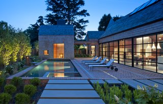 Outdoor lounge chairs by Richard Schultz sit on brick floors. The pool’s changing pavilion features a full bathroom.
