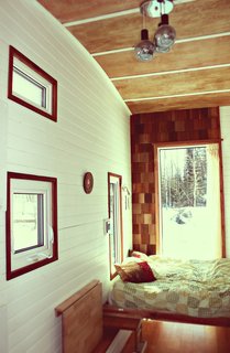 A custom Murphy bed occupies the rear end of the trailer, next to a wall of cedar shingles. The wall at left, which Herbert painted white, is tongue-and-groove pine.