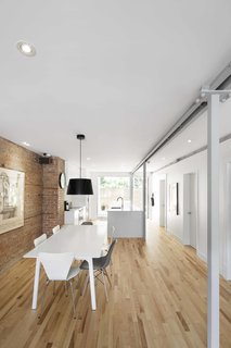 A linear layout allows for air and light to flow freely through the apartment, making it an a open haven in the center of the city. An IKEA pendant and chairs surround a table by Zone Maison.
