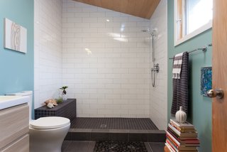 The bathroom features white and black tile and a small rock bed.
