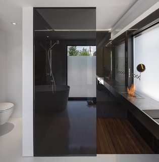 In the bathroom, a small bioethanol EcoSmart burner, along with radiant hydronic in-floor heating, provides warmth in a stark space.
