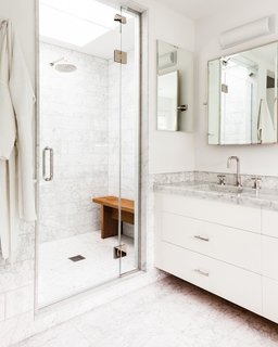 The master bathroom’s countertops are detailed with the same Carrara marble seen in the kitchen. The faucet and shower trims are by Kallista.