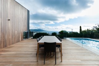 A Mood Outdoor Table by Studio Segers for Tribù is surrounded by Terra Outdoor Chairs by Bram Bollen, also for Tribù. They rest atop silvertop ash hardwood decking.