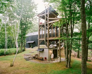 A Passive House and "Sauna Tower" Join a 19th-Century Barn in the Hudson Valley - Photo 2 of 13 - Connected to the main house by a narrow bridge, a three-story cedar tower with a sauna at its base recalls a tree house. The screened-in second level includes a table and chairs for enjoying an outdoor meal, while a swing on the tower’s top level provides a perch to take in the surrounding birch trees.
