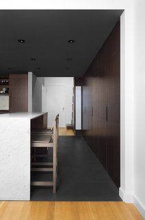 What was formerly a hallway is now integrated with the kitchen. A bank of floor-to-ceiling cabinets offer storage and an island covered in Carrara marble offers space for working or dining. The barstools are from CB2.