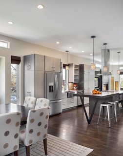 "Because the property is so narrow, we had to be strategic in laying out the plan," Mitchell says. "Our goal was to create an open plan that spanned from exterior wall to exterior wall in order to make the home feel as large as possible." Solid oak flooring fills the space and pendants from Kenroy Home illuminate the kitchen.