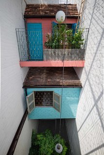 8 Small and Unexpected Garden Oases Hidden in the Middle of Cities - Photo 3 of 8 - In Saigon, courtyard-facing balconies are common and allow residents to be simultaneously outside while still being in the privacy of their own home. Here, flowers on the railing and a large tree in the courtyard below bring life to a narrow space.