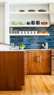 The residents have a particularly strong sense of color and love to cook with their son, so no-fuss finishes likes these blue tiles from Heath Ceramics were an ideal choice. The tiles combine with colorful tableware and custom walnut cabinetry to make a vibrant interior.