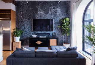 In the open-plan living area, a wall covered in Calico’s Lunaris Midnight—inspired by moonscapes and outer space—sets the tone for a vignette of darker furnishings, including a vintage credenza that doubles as an entertainment center, equipped with a Sonos Playbar.