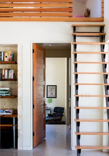 A custom steel and red oak ship ladder in the main living area is another space-saving solution. The door is Douglas fir and the shelving is mesquite wood; an Eames lounge chair can be seen in the master bedroom.