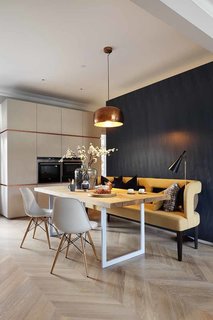  The open dining room exemplifies a clients’ wish for a "fun yet minimalist" home. A copper Habitat pendant lamp hangs above a solid oak dining table fabricated by INTERIOR-iD. A whimsical mustard sofa pops against the blue Tabu veneer wall. Rather than competing, each piece brings a sense of tactility and warmth to the table, ultimately creating a unified look.