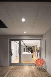 The new patio space is used as a semi-enclosed yard, allowing for privacy within a comfortable, urban space. The terrace is covered in light gray marine plywood, which is resistant to Quebec’s harsh seasons. The orange Chaise Solaire chair is by Fabio Fabiano and Michelange Panzini.