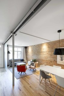 Vintage chairs and a sofa reference the history of the apartment building, complementing the impact of the original brick wall.