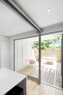 An aluminum-framed door leading to the terrace provides an added sense of depth, integrating outside with inside. Here, the metal contrasts sharply with the natural birch flooring.