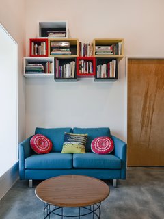 However, relying solely on concrete was not the best use of the budget, so Mulvena "balanced the concrete floors and highlights with a simple palette of affordable but industrial materials: black steel and plywood." The couch is by BoConcept.