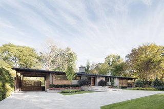 How to Refresh a Midcentury Gem in Quebec? Winter-White Everything - Photo 2 of 12 - It was important to the owners that the architects leave intact several distinctive details of the original home, such as the huge central chimney, which the architect calls, "The soul of the family home." Its natural stone complements the continuous cedar roof.