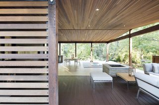 How to Refresh a Midcentury Gem in Quebec? Winter-White Everything - Photo 3 of 12 - The mix of stone, masonry, and wood in the south-facing terrace replicates the style of the original house. In order to ensure the space felt warm and inviting, the architect replaced the existing steel structure with solid cedar, adding cedar posts and shutters to unite the wood ceiling with both the interior and with nature outside.