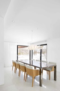How to Refresh a Midcentury Gem in Quebec? Winter-White Everything - Photo 10 of 12 - Playful stylistic details, such as two-toned dining chairs from Latitude Nord and a creative lighting fixture from Au Courant, are juxtaposed with the rest of the home’s tranquil elegance.