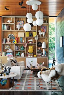 Jonathan Adler and Simon Doonan Go Trippy Contemporary on Shelter Island - Photo 2 of 12 - The site-sensitive exterior belies an interior festooned with a kaleidoscopic mix of colors and an array of tactile materials. The Peter rug, Malibu sofa, and ceramics are Adler's own designs. The tables, pendant lights, and rocker are vintage. Adler and Doonan used scaffolding from the house's construction to build the bookshelf.